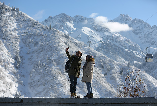 Tourist take a selfie with the backdrop of Tien Shan mountains after a recent snowfall in Almaty, Kazakhstan November 13, 2018. REUTERS/Pavel Mikheyev